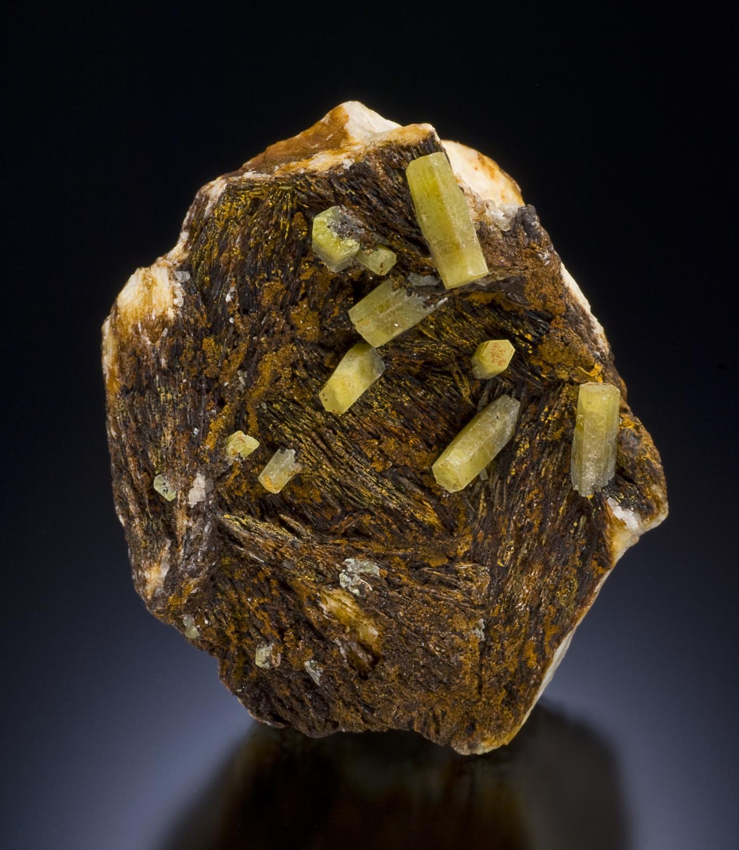 apfelgrüne Pyromorphitkristalle in Form von langgestreckten sechseitigen Tönnchen sitzen auf einer braunen Matrix aus Baryt