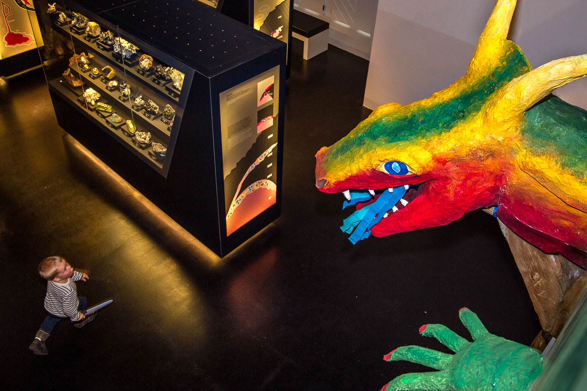 Kind in Ausstellung bestaunt großen bunten Fantasydrachen