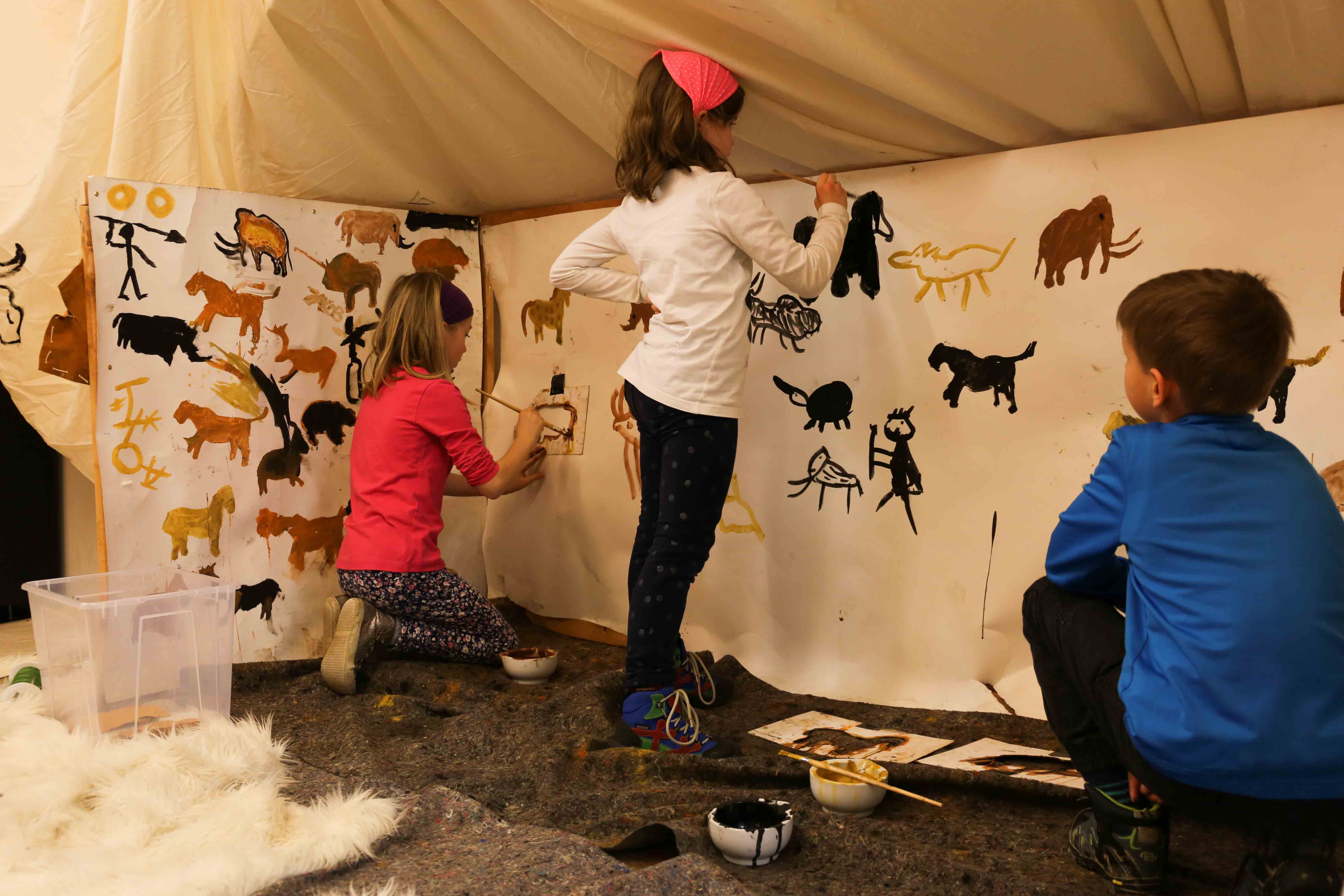 Kinder malen Eiszeitwesen auf grosse Leinwand